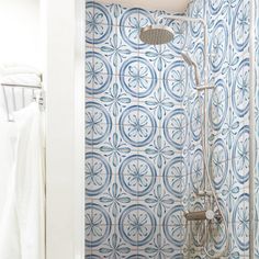 a bathroom with blue and white tiles on the wall, shower head and hand held showerhead