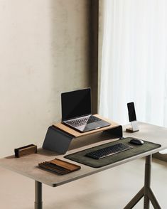 a laptop computer sitting on top of a wooden desk next to a keyboard and mouse pad