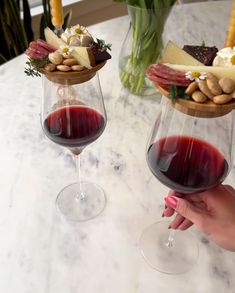 two wine glasses with different types of food in them sitting on a table next to each other