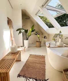 a white bathroom with a skylight above the bathtub and rugs on the floor