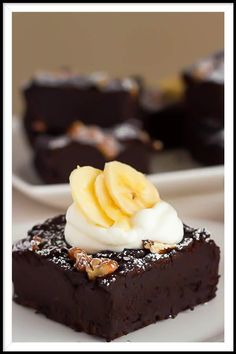 a piece of chocolate cake with whipped cream and bananas on top, sitting on a white plate