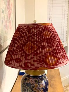 a lamp that is sitting on top of a table next to a window with blinds