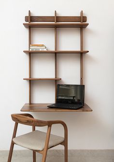 a laptop computer sitting on top of a wooden desk next to a book shelf filled with books