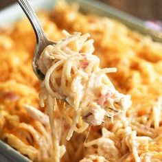 a spoon full of macaroni and cheese being lifted from a casserole dish