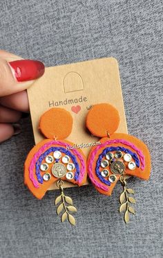 a pair of orange and pink earrings on top of a card