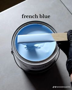 a person is holding a paintbrush over a can of blue liquid with the words french blue on it