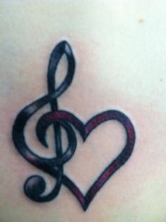 a music note tattoo on the back of a woman's stomach, with a treble in the shape of a heart