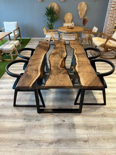 a dining table made out of wooden planks with chairs around it and grass in the background