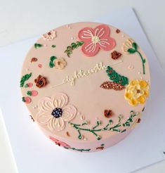 a pink cake with flowers and butterflies on it's side that says, elizabeth