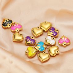 several heart shaped charms sitting on top of a pink cloth with gold trimmings