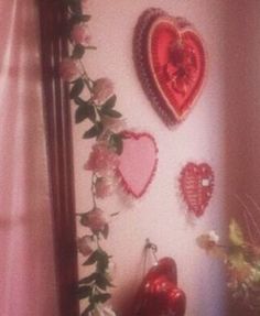 three heart shaped balloons are hanging on the wall next to a vase with flowers in it