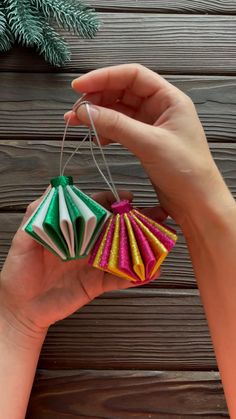 a hand holding three small ornaments in different colors