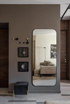 a living room with a couch, mirror and pictures on the wall in front of it