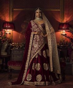 a woman in a red and gold bridal gown with her hands on her hips