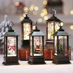 three christmas lanterns with santa claus and snowman on them, sitting next to each other