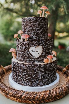 a chocolate wedding cake with mushrooms on the top and hearts in the middle is sitting on a wicker platter