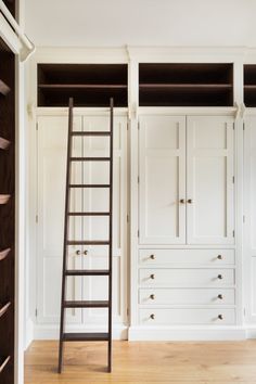 an empty room with white closets and ladder