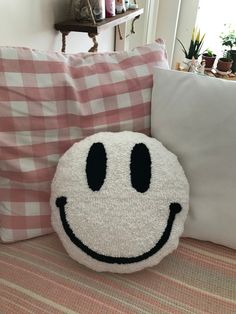 a smiley face pillow sitting on top of a bed