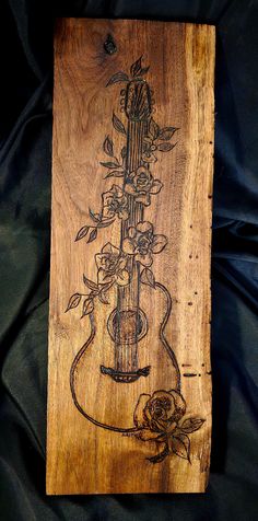 a wooden plaque with an image of a guitar and flowers on it's side