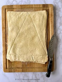 an uncooked pizza dough on a cutting board with a knife