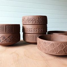 four brown bowls sitting on top of a wooden table