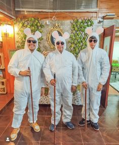 three men dressed in white bunny ears and holding canes standing next to each other