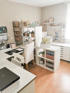 an office with white desks and shelves filled with books, papers and other items