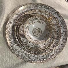 a white and gold dinner set on top of a table with napkins next to it