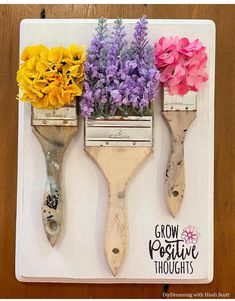 three flower brushes with flowers in them sitting on a table