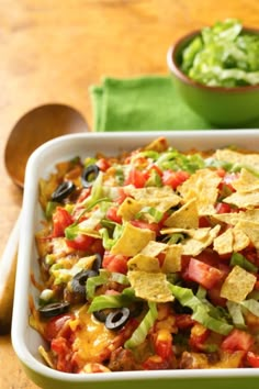 a white casserole dish filled with nachos and tortilla chips