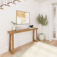 a wooden table sitting under a stair case next to a vase with a plant on it