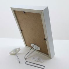 a cork board with two clips and a stapler on it next to some screws