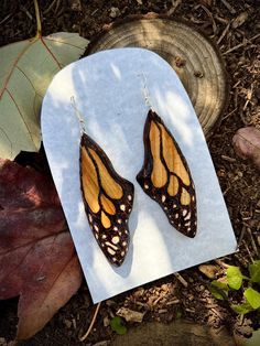 a pair of butterfly wings sitting on top of a piece of paper next to leaves