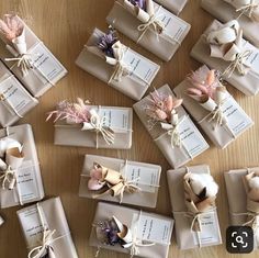 many wrapped gift boxes on a table with ribbons and tags tied around the top one