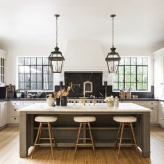 a large kitchen with white cabinets and wooden stools in front of an island counter