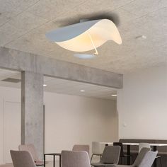 an empty conference room with chairs and tables in the center is lit by a circular light fixture