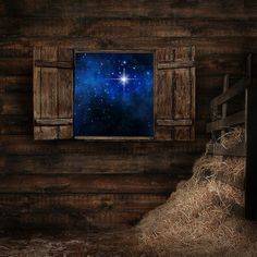 an old barn with hay bales and a window that has a view of the night sky