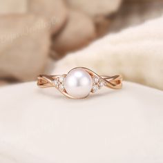 a pearl and diamond ring sitting on top of a white blanket