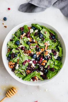 a white bowl filled with blueberries and spinach salad on top of a table