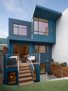 a blue house with stairs leading up to the upper floor and second story window area