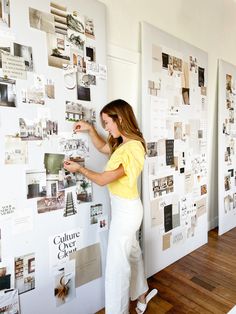 a woman standing next to a wall covered in pictures