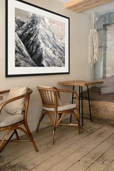 two wooden chairs sitting next to each other in front of a painting on the wall