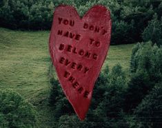 a large red heart with words written on it in the middle of a green field