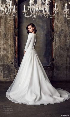 a woman in a white wedding dress standing next to a chandelier