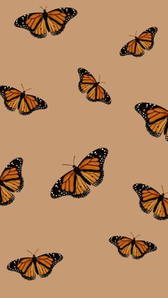 a group of butterflies flying in the air on a brown background with black dots and white spots