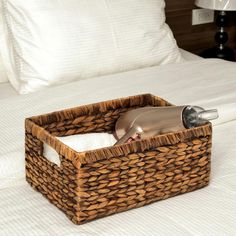 a bed with white pillows and a brown basket on top of it that has a hair dryer in it