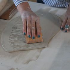 a woman with blue nails is working on a piece of pottery