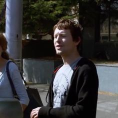 two people standing next to each other on a sidewalk with trees in the back ground