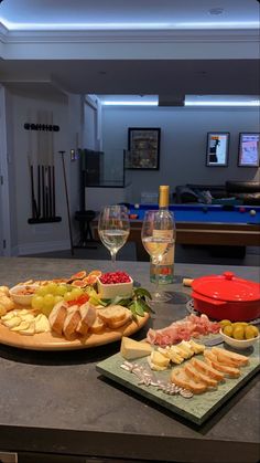 two plates with food and wine on a table in front of a pool, near a glass of wine