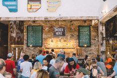 a group of people sitting at tables in front of a brick wall with menus on it